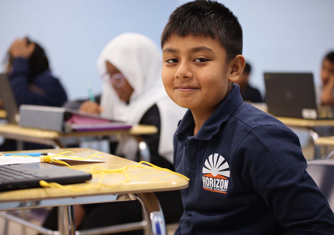 Elementary student smiling and posing together in a classroom.